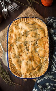 a pie sitting on top of a wooden table next to silverware and utensils