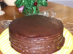 a chocolate cake sitting on top of a wooden table next to a green tree branch