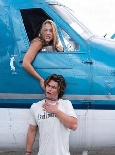 a man standing next to a woman in front of an airplane