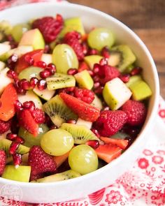 a white bowl filled with fruit salad on top of a red and white table cloth