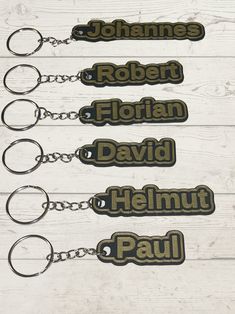 four keychains with the names of five different people on them, all in black and gold