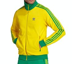 a man in yellow adidas jacket and green pants posing for the camera with his hands on his hips