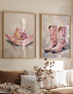 two paintings hang above a couch in a living room with pillows and blankets on it