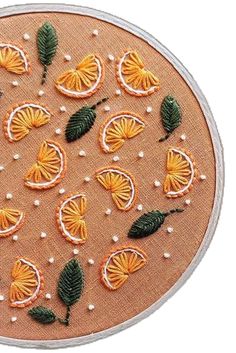 an embroidery project with oranges and leaves