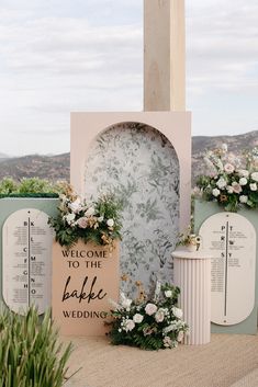 an outdoor ceremony setup with floral arrangements and a welcome to the bake wedding sign