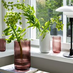 three vases with plants in them sitting on a window sill next to a lamp