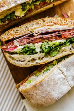 two sandwiches cut in half sitting on top of a cutting board next to each other