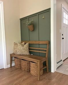 a wooden bench sitting in the middle of a hallway next to a door with baskets on it