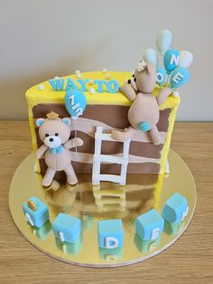 there is a cake that has two teddy bears on it and blue balloons in the air