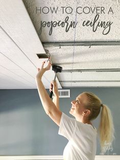 a woman is painting the ceiling in her living room