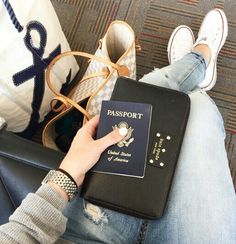 a person sitting on a couch with a passport and purse in front of their feet