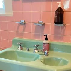 a green sink in a bathroom with pink tiles on the wall behind it and two soap dispensers