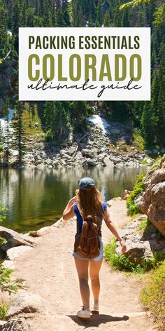 a woman walking down a dirt path next to a lake with text overlay reading packing essentials colorado ultimate guide