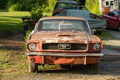 an old rusted out car sitting in the dirt