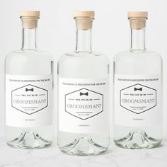 three bottles of groomsman's gin on a marble surface