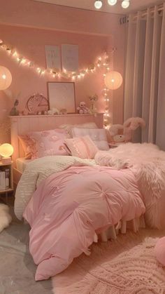 a bedroom decorated in pink and white with lights strung from the ceiling, bedding and pillows