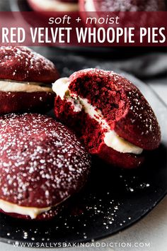 some red velvet cookies with white frosting on a black plate next to another one