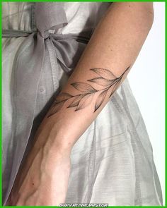 a woman's arm with a tattoo on it that has leaves in the middle