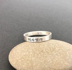 This listing is for a personalized engraved Korean name ring in burnished matte sterling silver. The sample ring is engraved with a name Isabella in Korean in the font #1. Please check the font options in the pictures. Outside and/or inside of the ring can be engraved.  The sample ring is about 3 mm wide.  All orders come gift-wrapped. Avoid dust, moisture and direct light to ensure the jewelry does not tarnish and discolor. << How to order >> Please choose engraving side and ring size from the options. Please leave a name (word, phrase) and font style number you want. We'll translate a name for you if you don't know the language. If you don't choose a font, the font used for the sample will be used and the font #2 will be used for numbers. Promise Sterling Silver Engraved Ring, Promise Sterling Silver Ring With Engraved Text, Symbolic Engraved Stackable Rings For Anniversary, Meaningful Engraved Silver Stackable Rings, Silver Engraved Name Ring For Wedding, Personalized Engraved Ring For Promise, Symbolic Personalized Engraved Promise Ring, Symbolic Personalized Sterling Silver Engraved Ring, Symbolic Sterling Silver Engraved Ring, Personalized