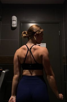 a woman standing in front of a mirror with her back turned to the camera and wearing blue shorts