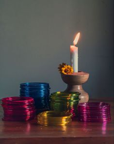 a lit candle sitting on top of a wooden table next to stacks of colorful plates