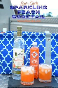 two bottles of sparkling peach cocktail on a tray with ice and oranges next to it