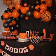 an orange and black birthday party with basketballs on the wall, balloons and cake