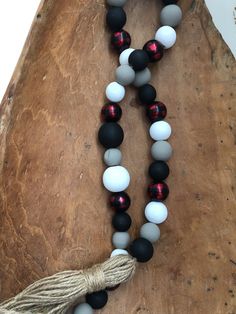 a black, white and red beaded necklace with tassels on a wooden board