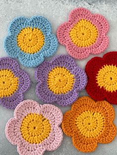 four crocheted flower coasters sitting on top of a cement floor next to each other