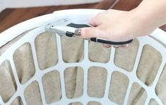 a person holding a cell phone in their hand over a white chair with holes on it