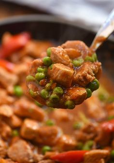 a spoon full of meat and vegetables being held up