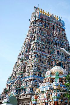 a very tall and colorful building with statues on it's sides at the top