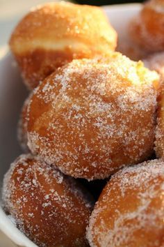 powdered sugar covered donuts in a white bowl