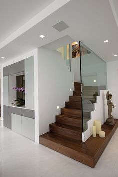 the stairs are made of wood and glass in this modern home with white walls and flooring