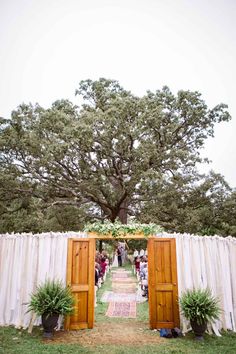 an outdoor ceremony with wooden doors and drapes