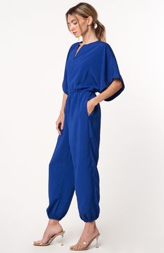 Relaxed sleeves and a tapered, jogger-inspired silhouette amplify the casual-cool style of this go-to jumpsuit. 55" length; 25" inseam; 9" leg opening (size Medium) Hidden front-zip closure Split neck Short sleeves Side-seam pockets Elastic waist Elastic ankle cuffs Unlined 100% polyester Dry clean or hand wash, dry flat Imported Asian Owned/Founded Blue Jumpsuits And Rompers With Elastic Waistband For Spring, Blue V-neck Relaxed Fit Jumpsuits And Rompers, Blue V-neck Relaxed Fit Jumpsuit, Relaxed Fit Jumpsuits With Elastic Waistband For Work, Ankle Cuffs, Cool Style, Elastic Waist, Top Brands, Split