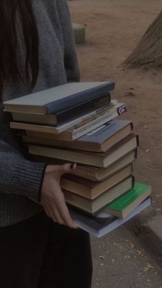 a woman holding a stack of books in her hands