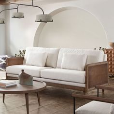 a living room with white couches and wooden tables in front of a circular wall