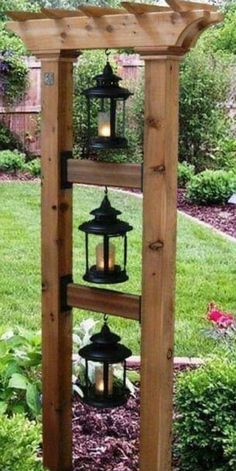 a wooden structure with lanterns hanging from it's sides in the middle of a garden