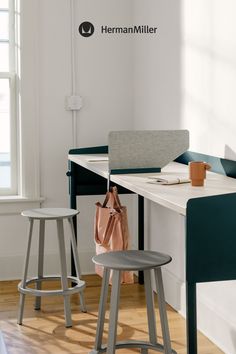 two stools in front of a desk with a bag on it