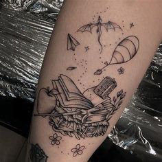 a tattoo on the leg of a person with an open book and flying kites