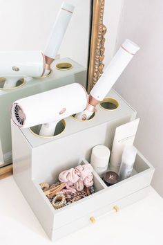 a white box with some items in it next to a mirror and a hair dryer