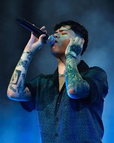 a man with tattoos on his arms and chest holding a microphone in front of his face