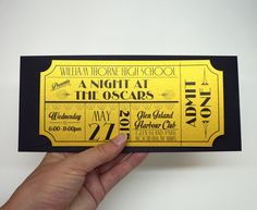 a person holding up a ticket for an oscars show in front of a white wall