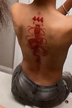 the back of a woman's body with red ink on her stomach and head