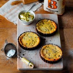 three mini quiche pies on a cutting board next to some condiments