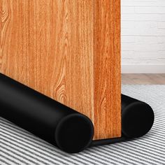 a close up of a black speaker on a wooden floor near a brick wall and striped carpet