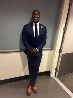 a man in a suit and tie standing next to a wall