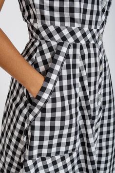 a woman is wearing a black and white checkered dress with buttons on the side