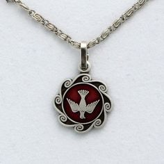 Red enameled Holy Spirit pendant with
18in. silver plated scroll chain. Silver Enamel Charm Necklace With Round Pendant, Silver Enamel Round Pendant Charm Necklace, Silver Enamel Jewelry With Adjustable Chain, Red Enamel Round Pendant Necklace, Silver Enamel Pendant Charm Necklaces, Red Symbolic Engraved Jewelry, Red Metal Jewelry With Silver Chain, Red Pendant Charm Necklace In Metal, Red Engraved Round Pendant Jewelry